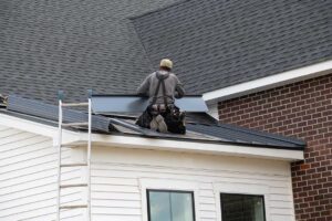 Workers protect a shingled roof with secured coverings while renovating an upper-floor room.