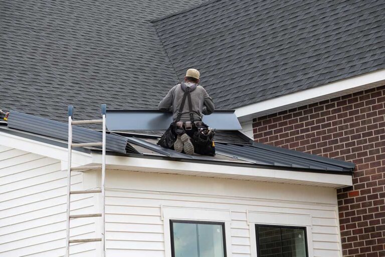 Workers protect a shingled roof with secured coverings while renovating an upper-floor room.