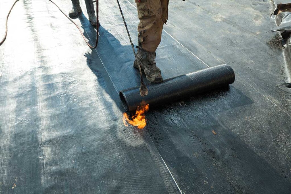 Person in slip-resistant shoes carefully walking across a dry shingle roof beside a secured ladder.