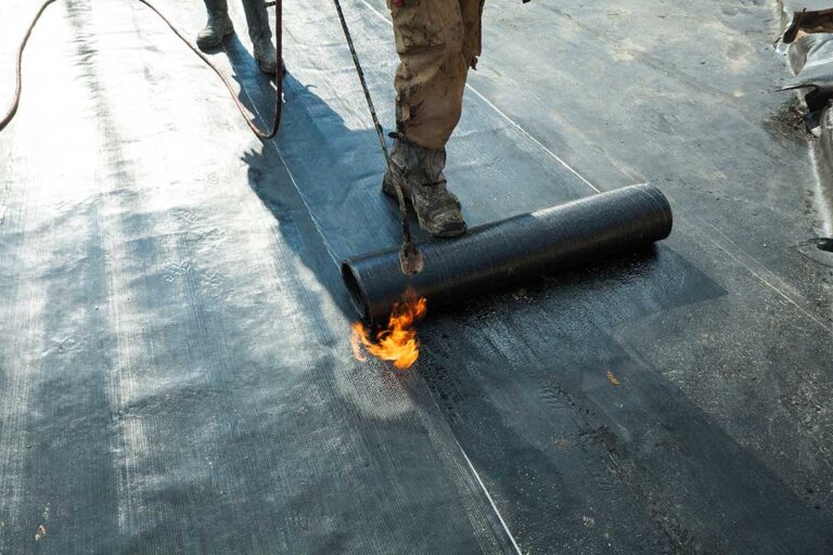 Person in slip-resistant shoes carefully walking across a dry shingle roof beside a secured ladder.